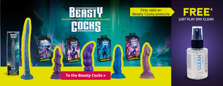 Advertisement with a purple background and yellow text that says 'FREE JUST PLAY 2IN1 CLEAN'. “Only valid on Beasty Cocks products” can be seen underneath in smaller letters. A bottle of the toy cleaner is shown at the top in the right-hand corner. Five different dildos in various shapes and colours can be seen at the bottom against a mystical blue background. The brand name “Beasty Cocks - Supernatural Creature Dildos” is prominently displayed in white. There is a call-to-action button at the bottom with a red background and the words “To the Beasty Cocks »”.