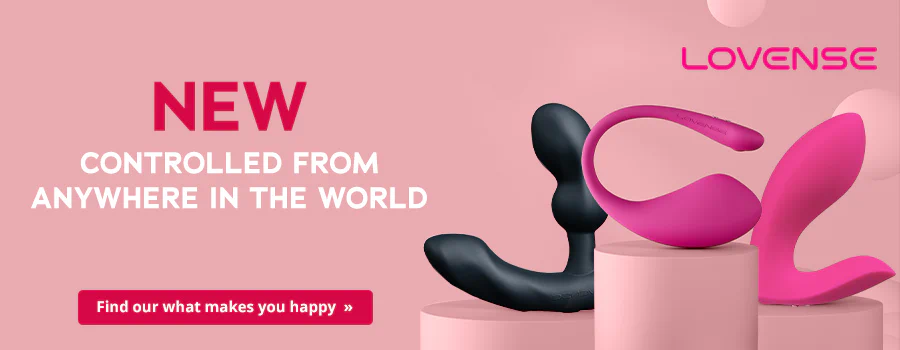 Advertisement with a pink background. 'NOW NEW' is written in large red letters at the top. The text 'CONTROLLABLE FROM ANYWHERE' is underneath in white letters. There are various Lovense products on the right – the products are in black and pink. The products are on pink pedestals. The Lovense logo in pink is at the top to the right. There is call-to-action button with a red background at the bottom of the advertisement with the white text 'Find out what makes you happy »'.